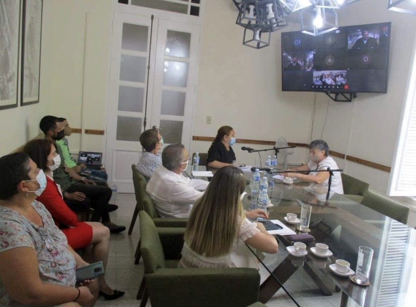 Люди в зале наблюдают за онлайн встречей на Кубе
