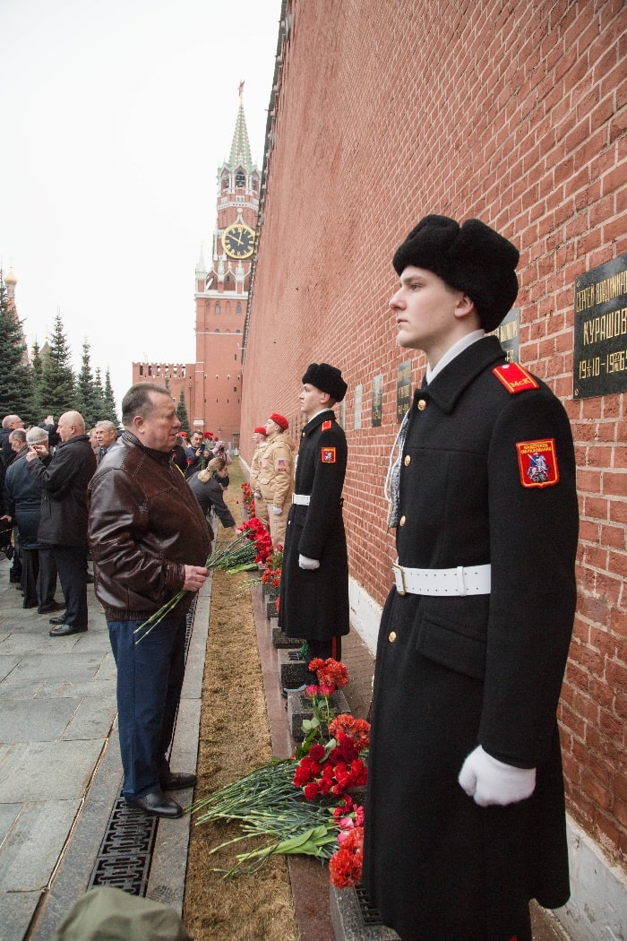 Мужчина возлагает цветы к могиле Ю.А. Гагарина у стен Кремля, а на фоне его стоят курсанты в карауле