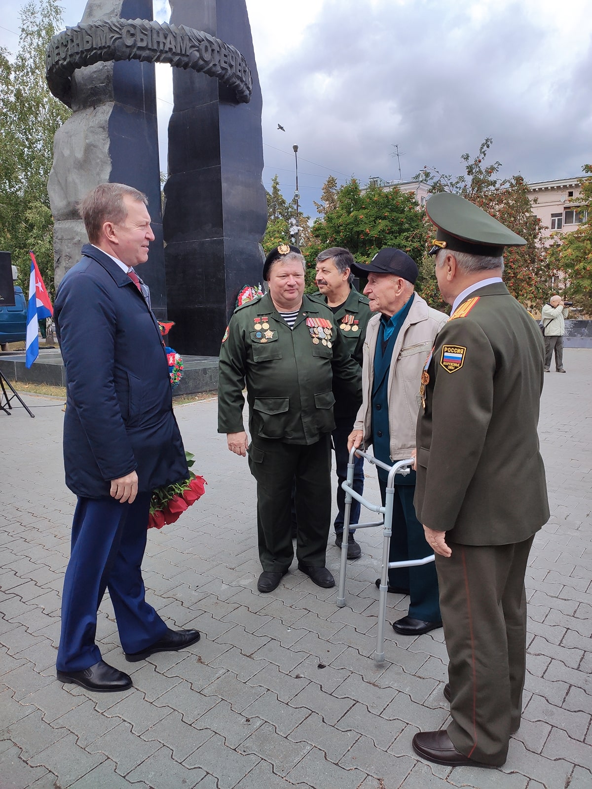 Андрей Пшеницын стоит напротив ветерана с цветами
