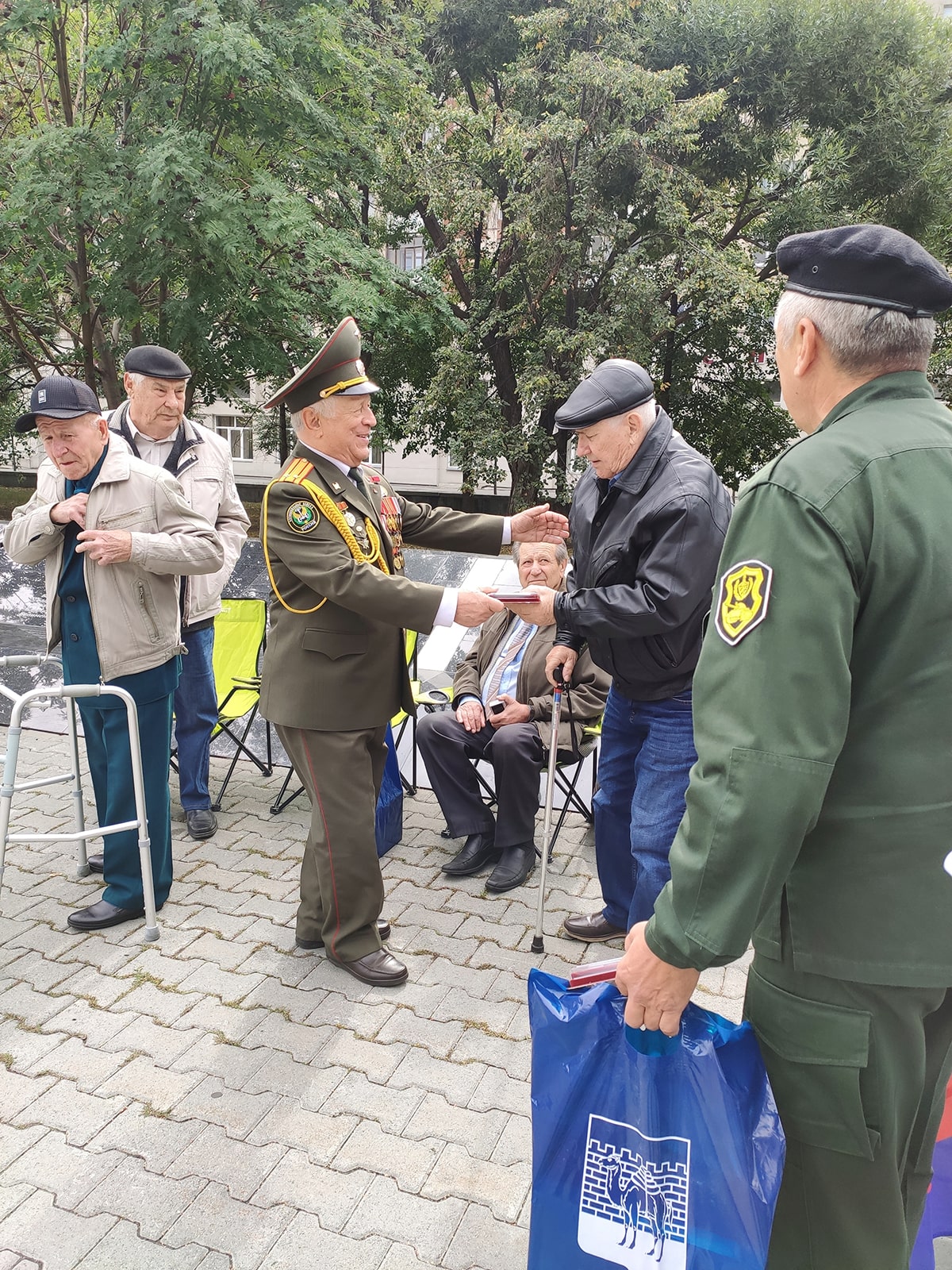 Мужчина в военной форме вручает ветерану медаль